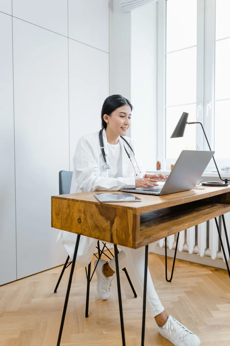 Healthcare provider using a laptop at a bright office desk